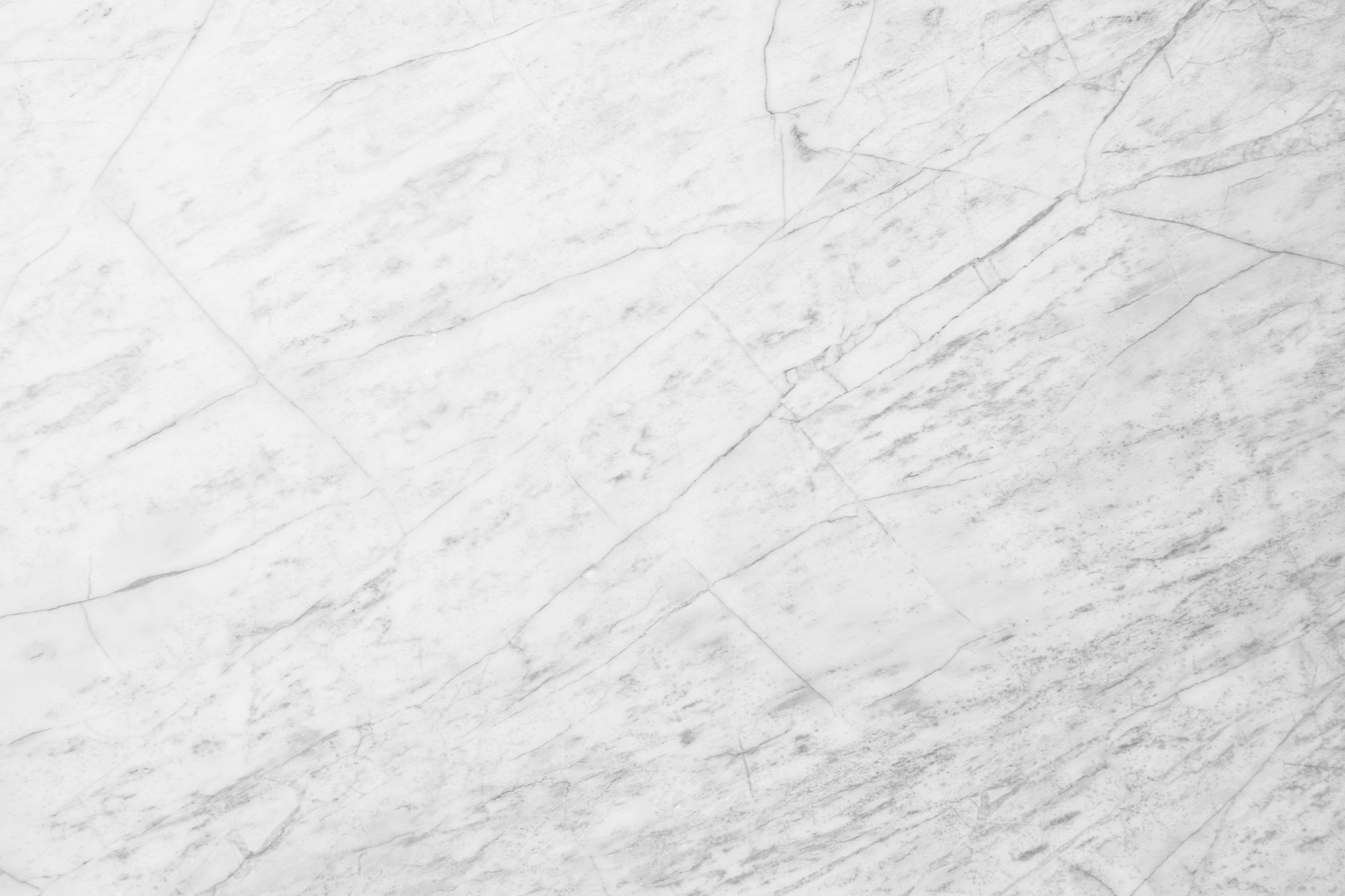 A high-resolution close-up of a white marble surface with natural veining patterns.