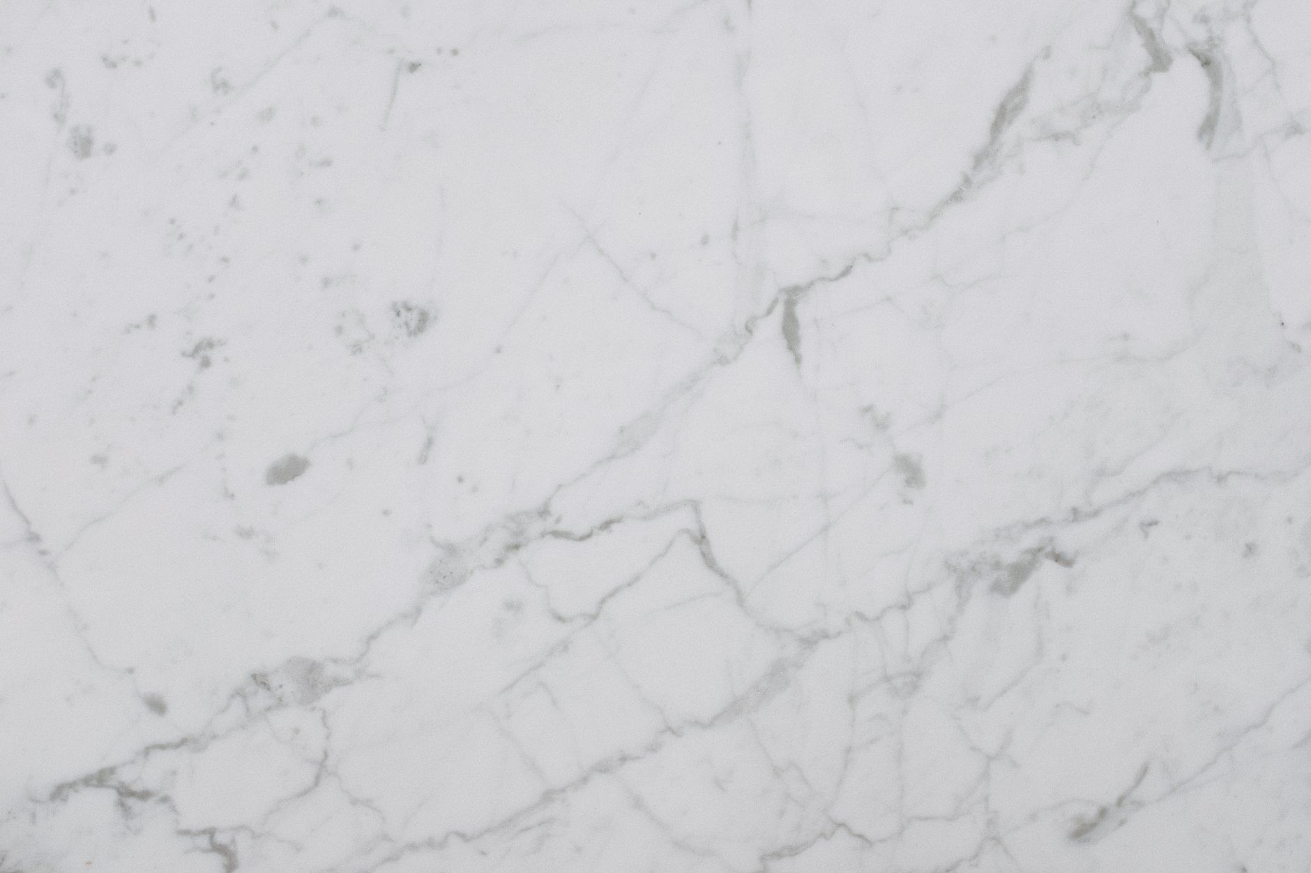 Smooth white marble surface showing natural veining and texture, perfect for design backgrounds.