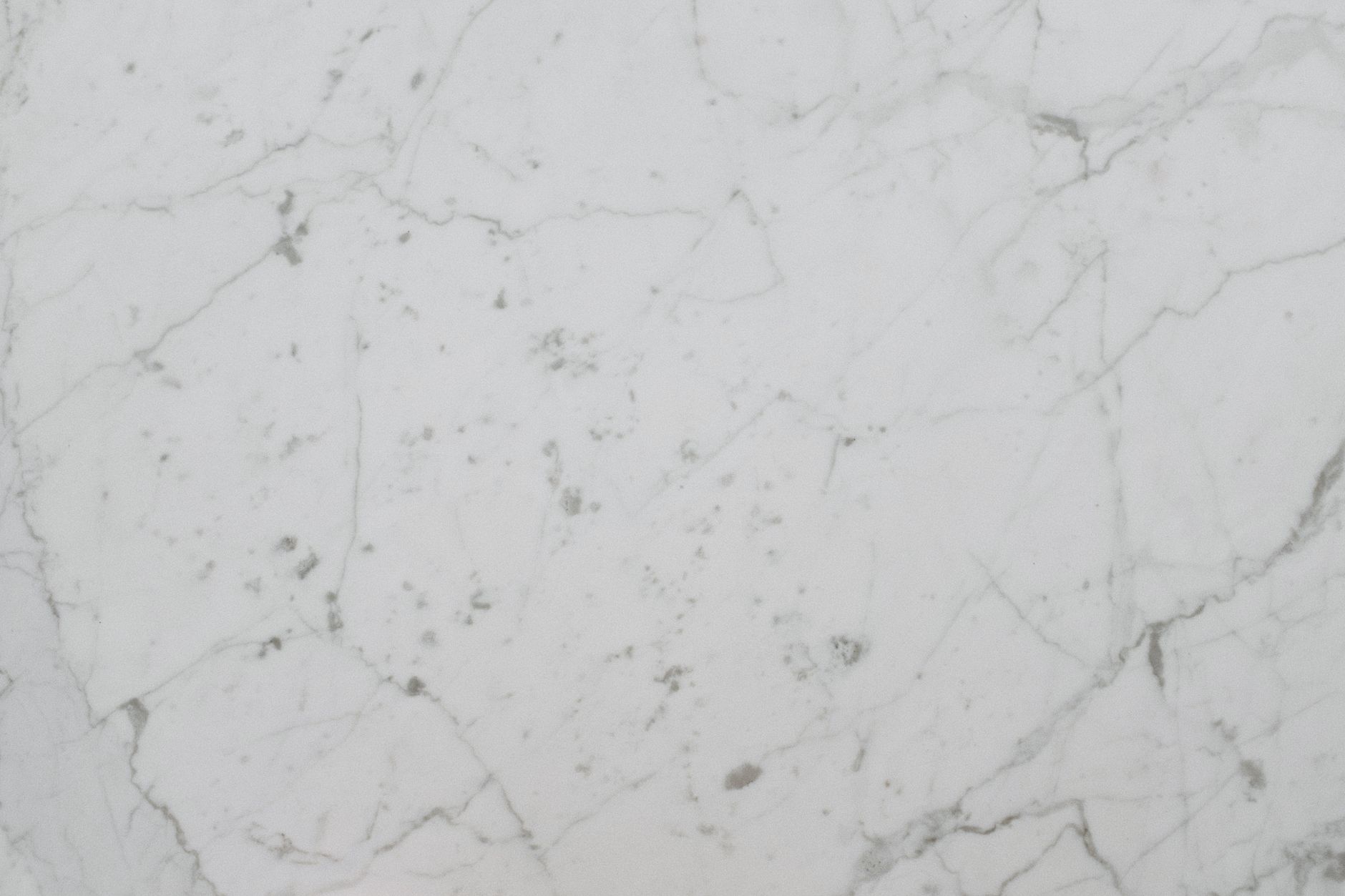 High-resolution image of a white marble surface with natural veining, ideal for backgrounds and design use.